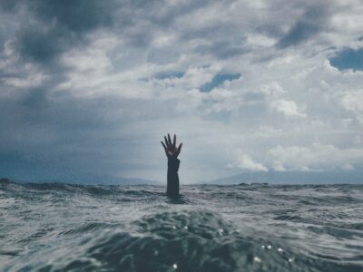 hand reaching up out of the ocean toward the sky